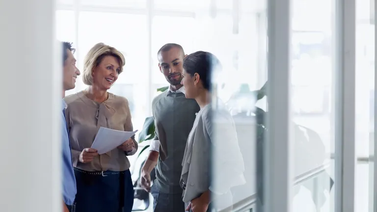 Smiling businesswoman discussing over document with colleagues in office.